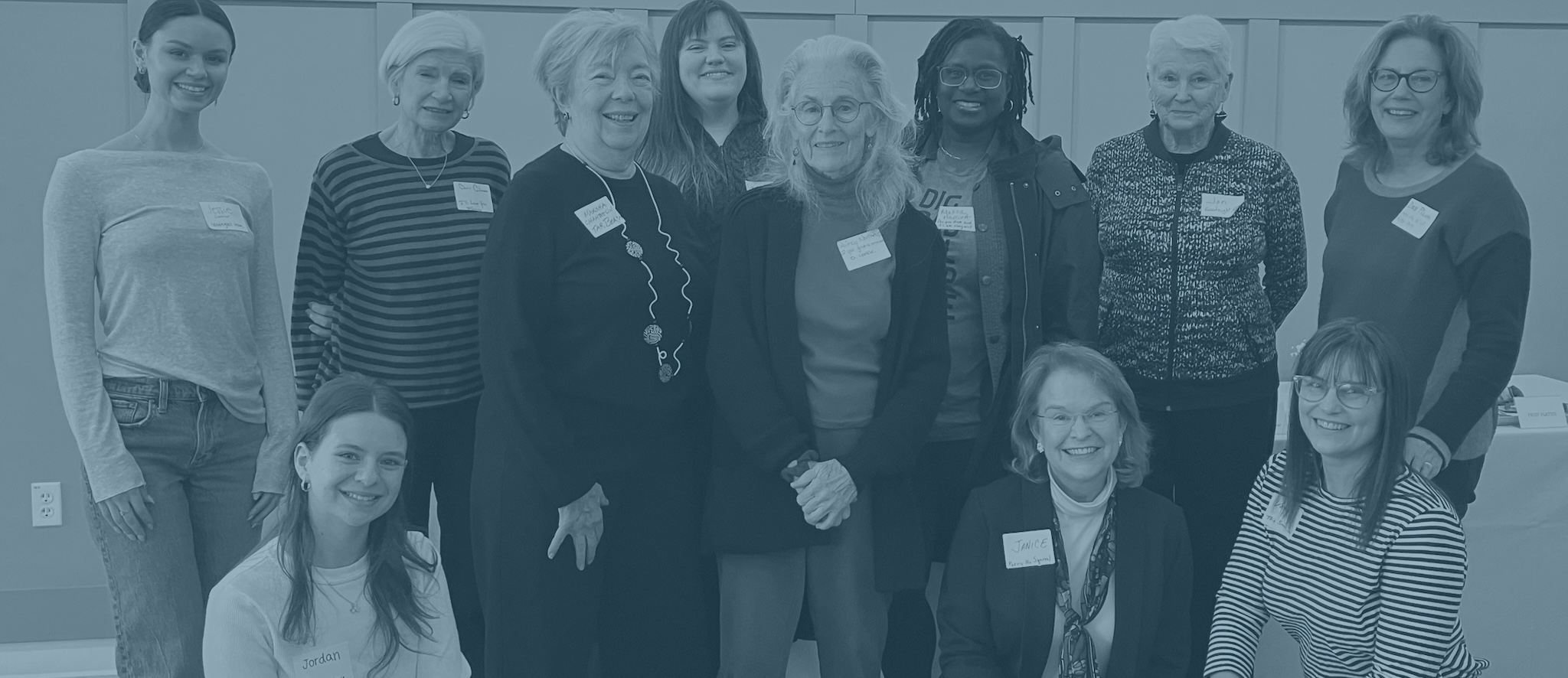 A team of women wearing name tags and smiling.