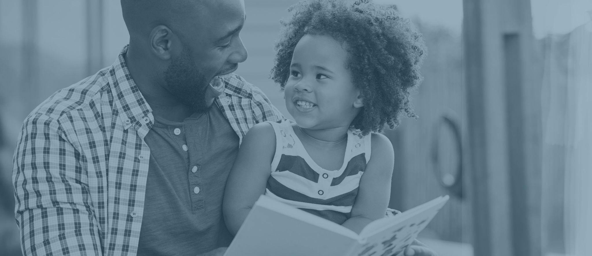 A father and his child smiling while holding a book.