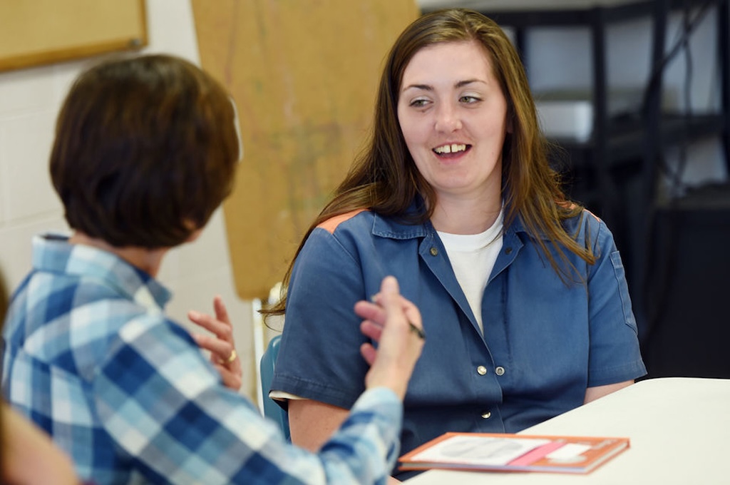 A volunteer talking with a smiling incarcerated mother.