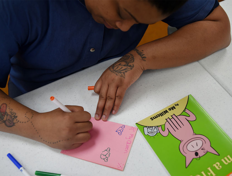 A young person writing a colorful note.
